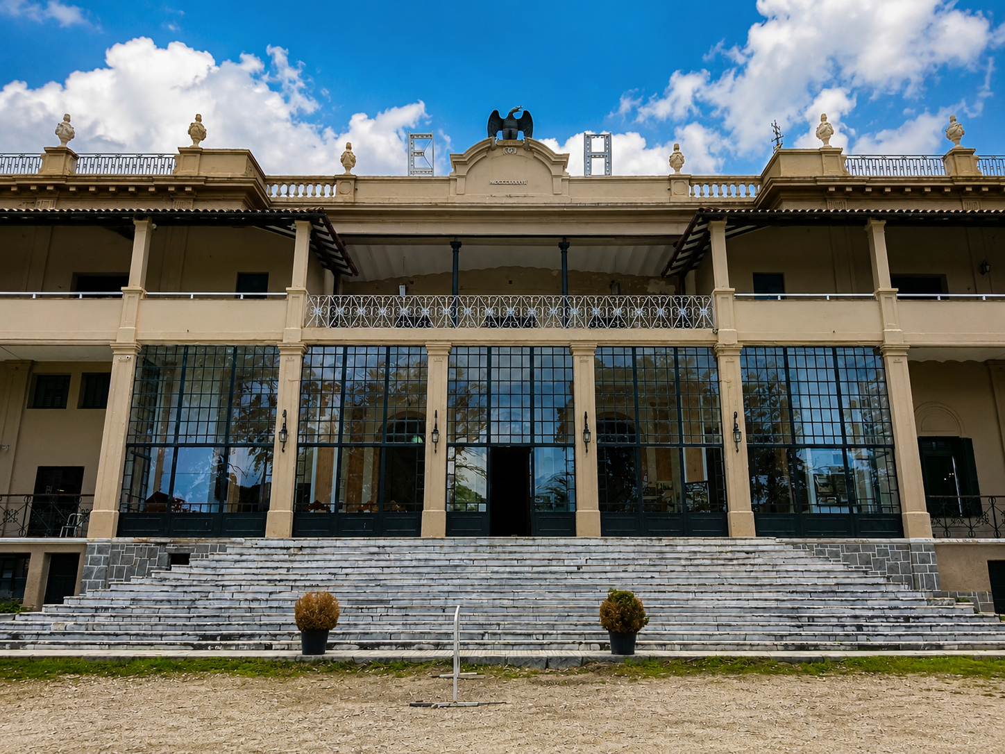 Facade of a historic building featuring grand staircases, large windows and classic architecture.